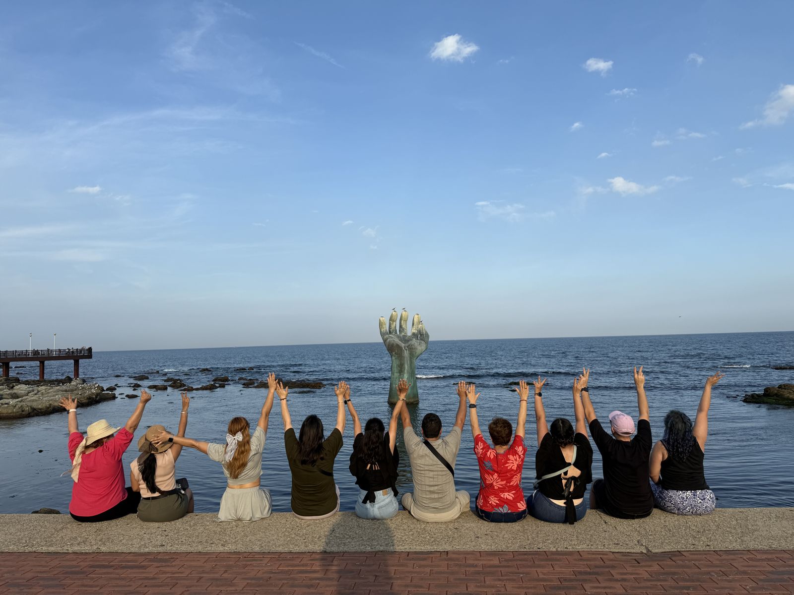 Grupo saludando frente a la escultura de la mano de Homigot en Pohang